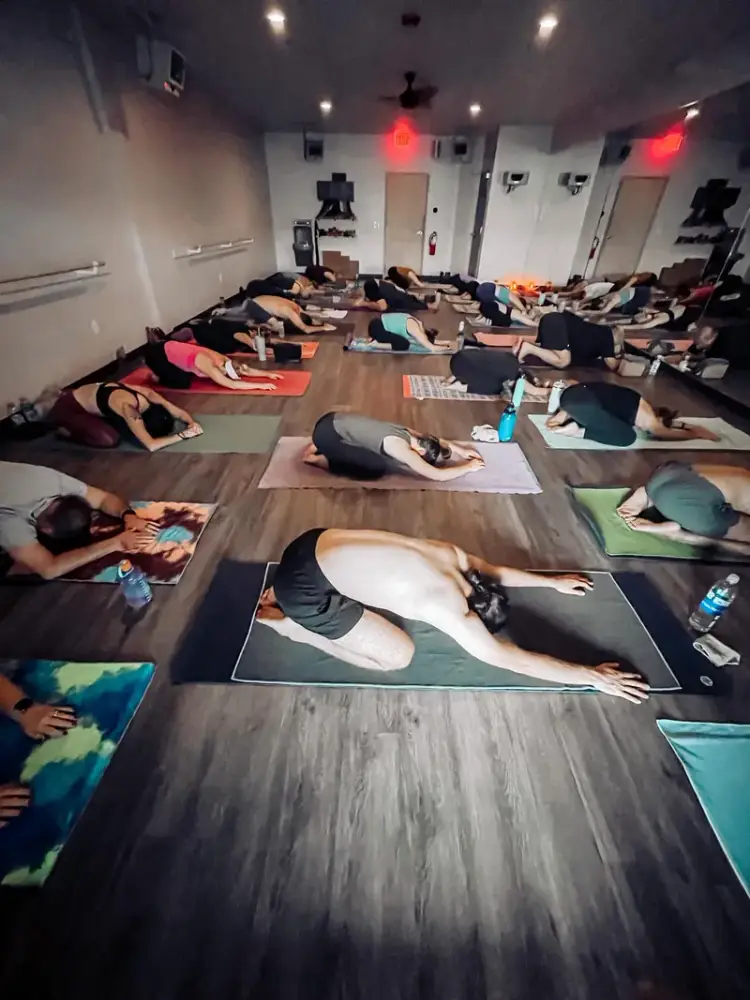 Students in child's pose during a hot yoga class